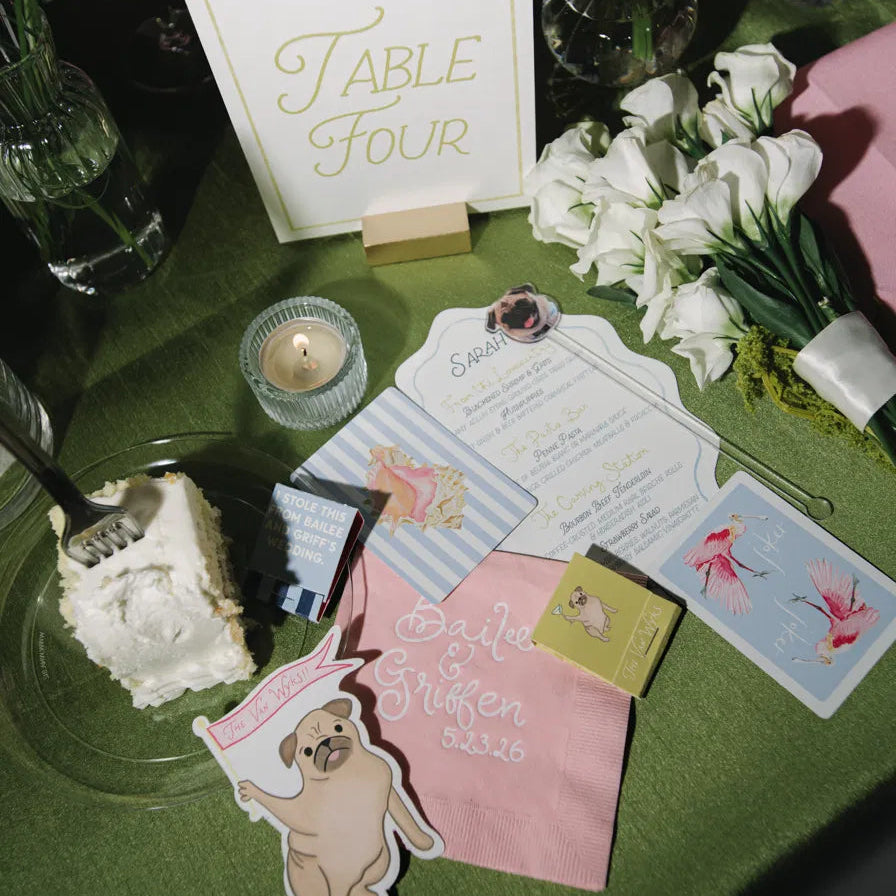 Custom personalized wedding place card and menu displayed with a personalized cocktail napkin, table number, and elegant reception décor.