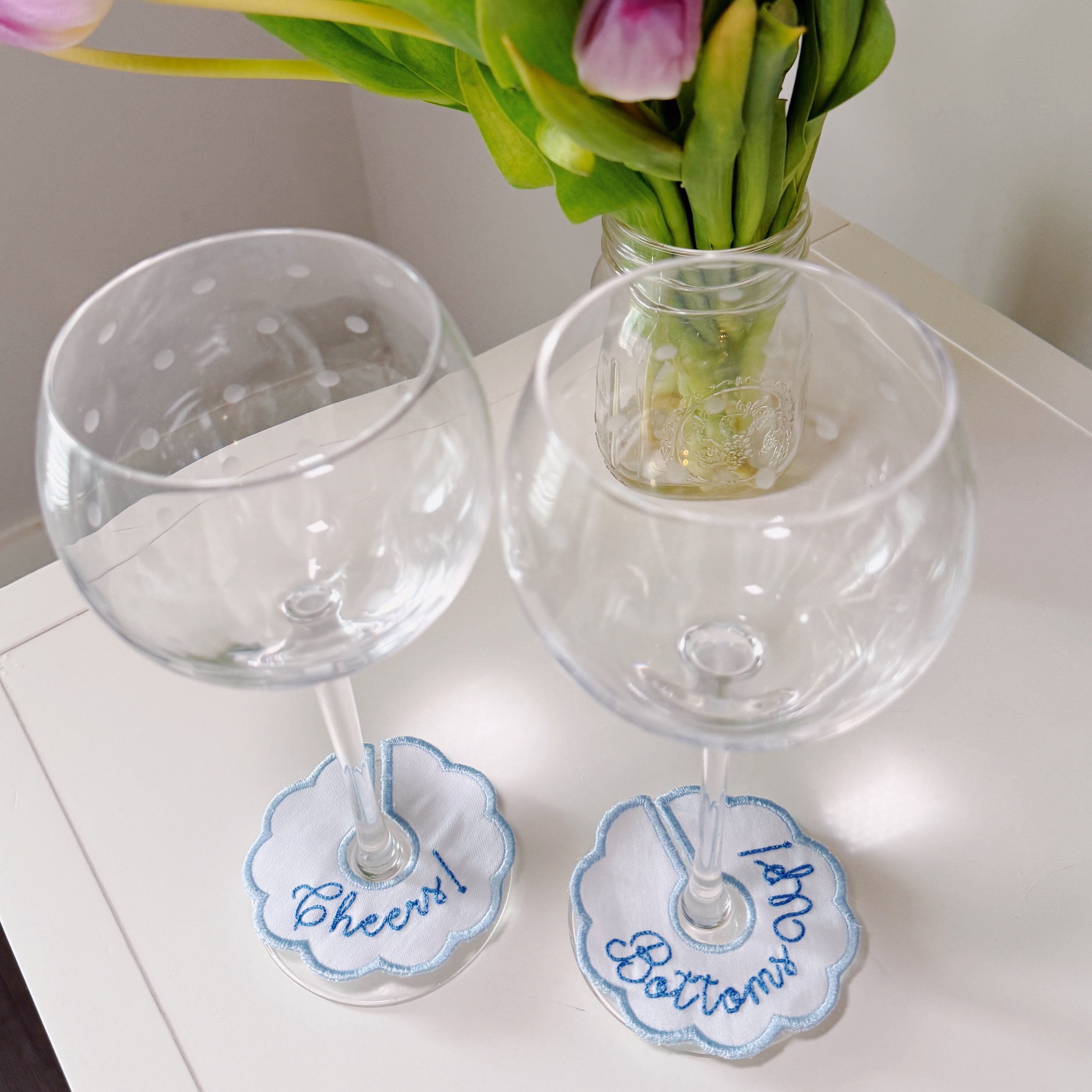 Personalized embroidered wine glass charms featuring custom sayings, designed to help guests identify their drinks at parties and celebrations.