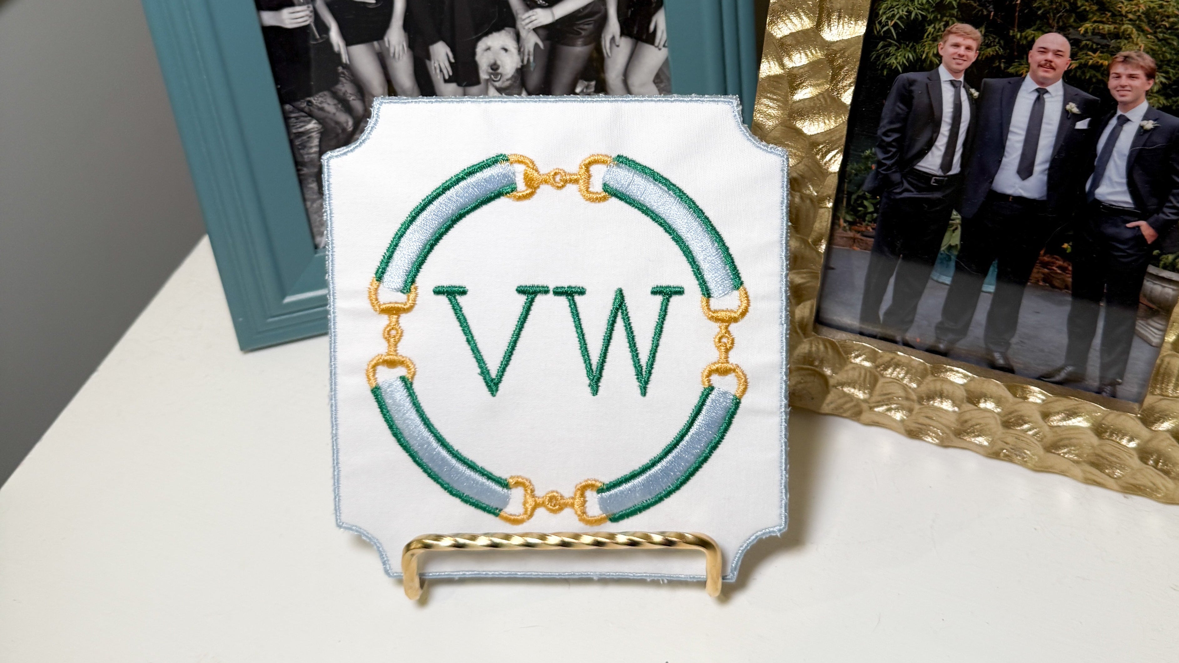 Personalized embroidered plaque display featuring a custom monogram and equestrian bit border, displayed on a decorative stand.